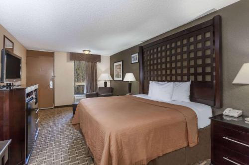 a hotel room with a large bed and a television at Super 8 by Wyndham Atoka in Atoka