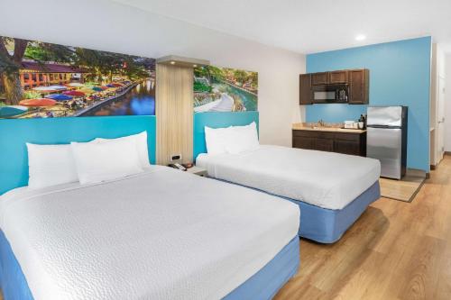 a hotel room with two beds and a kitchen at Days Inn & Suites by Wyndham San Antonio near Frost Bank Center in San Antonio