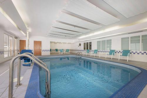 a swimming pool with chairs and a swimming pool at AmericInn by Wyndham Duluth in Duluth
