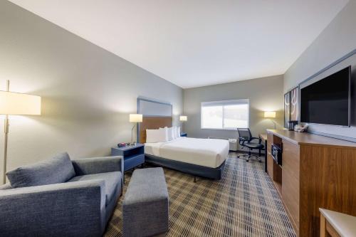 ein Hotelzimmer mit einem Bett, einem Sofa und einem TV in der Unterkunft AmericInn by Wyndham Duluth in Duluth
