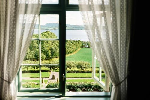 an open window with a view of a green field at Hoel Gård - Herregården ved Mjøsa in Nes i Ådal