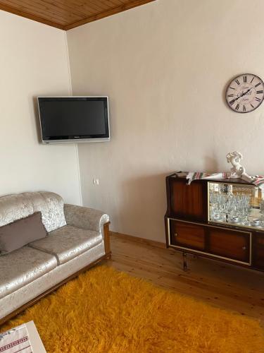 a living room with a couch and a clock on the wall at Agios Petros Studio in Áyios Pétros