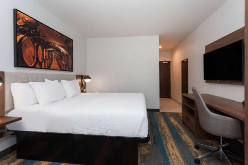 a hotel room with a bed and a desk and a computer at La Quinta Inn & Suites by Wyndham Galt Lodi North in Galt