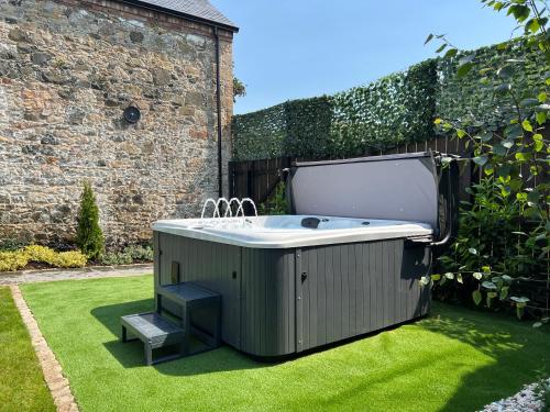 una vasca idromassaggio seduta sull'erba in un giardino di Converted Victorian Coach House with Hot Tub a Stewartstown