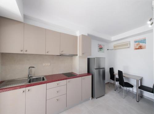 a kitchen with white cabinets and a stainless steel refrigerator at Boursinos cozy apartments in Lefkada Town