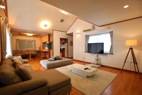 a living room with a couch and a flat screen tv at Guesthouse Akabana in Miyako-jima
