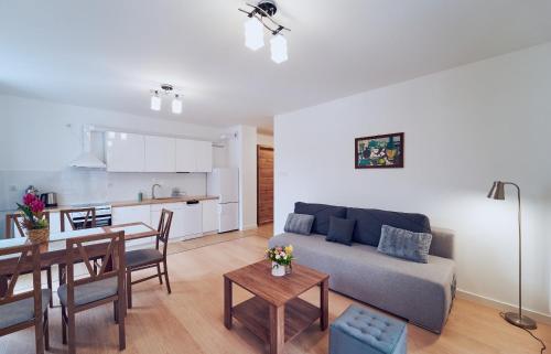 ein Wohnzimmer und eine Küche mit einem Sofa und einem Tisch in der Unterkunft Marel-Apartments Willa Fonte - apartament 8 in Polanica-Zdrój