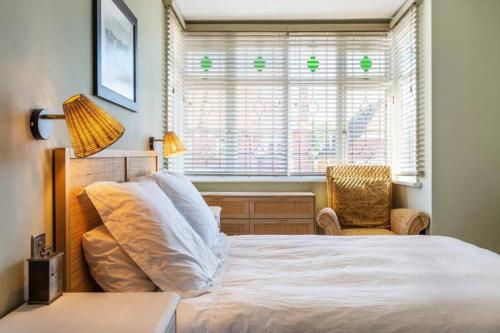 a bedroom with a bed and a chair and a window at Broadstairs Family Home in Kent