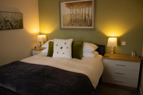 a bedroom with a large bed with two lamps at Buttermere Cottage in Banff