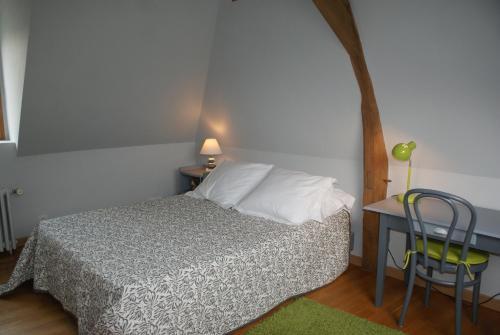 a bedroom with a bed and a table and a chair at Gite des Goganes in Denée