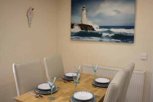 a dining table with chairs and a lighthouse on the wall at Buttermere Cottage in Banff