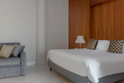 a bedroom with a large bed and a couch at Savoia Hotel Rimini in Rimini
