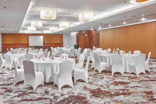 un salón de banquetes con mesas y sillas blancas y un podio en Crowne Plaza Manila Galleria, an IHG Hotel en Manila