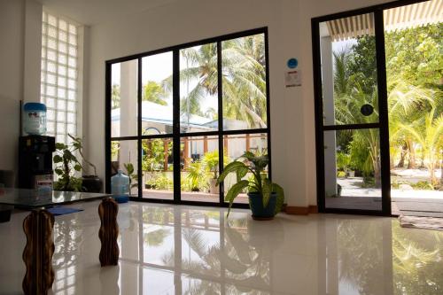 a living room with large windows and a white floor at Kudhi Boli Beach House in Thulusdhoo