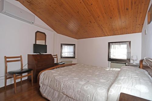een slaapkamer met een bed en een houten plafond bij Al lago Guest House in Revine Lago