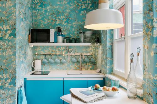 een keuken met blauwe kasten en bloemenbehang bij Chase Apartments-Boutiquehotel Style II in Würzburg