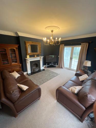 sala de estar con 2 sofás de cuero y chimenea en Field View, en Ashfield