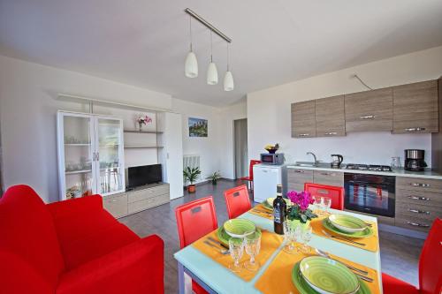a kitchen and living room with a table and red chairs at Legnoncino Holiday Home- Lake Como in Colico