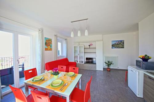 a kitchen and dining room with a table and red chairs at Legnoncino Holiday Home- Lake Como in Colico
