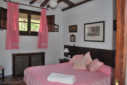 a bedroom with a pink bed with pink sheets and a window at Cortijo La Priorita in Córdoba