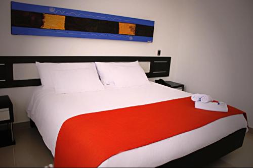 a bedroom with a large bed with a red and white blanket at Hotel Guaitipan Plaza in Pitalito