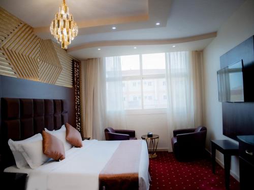 Habitación de hotel con cama grande y lámpara de araña. en نزل السلطان للأجنجة الفندقية, en Jazan