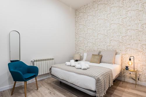 a bedroom with a bed and a blue chair at BNBHolder Ponzano & Chamberi I in Madrid