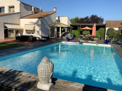 - une piscine avec une statue à côté d'une maison dans l'établissement Villa charmante à Nalliers avec piscine, à Nalliers