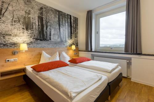 una camera da letto con un grande letto con due cuscini rossi di 3 Raum Wohnung Exklusiv a Schulenberg im Oberharz