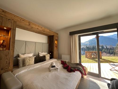 a bedroom with a large bed with a large window at Les Trois Chaufatons - Chalets Boutiques in Montriond