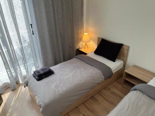 1 dormitorio con 2 camas, lámpara y ventana en Charcoal Thirteen Apartment, en Kavala