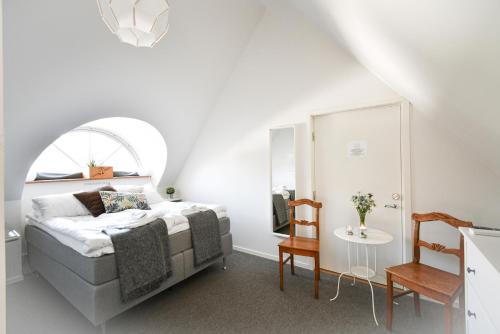 a white bedroom with a bed and a table at Kåseberga Gårdshotell & Spa in Kåseberga