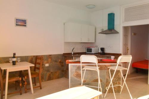 a kitchen with a table and chairs and a counter top at Apartamentos Playa Azul in Vallehermoso
