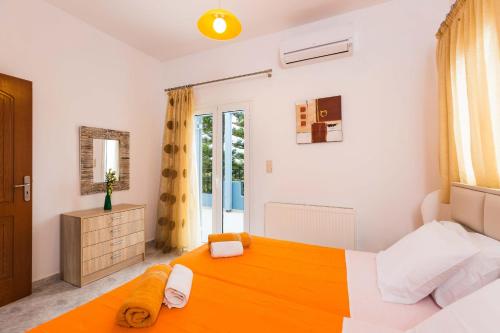 a bedroom with a large orange bed and a window at Blue Villa 1 - With Private Pool in Perama