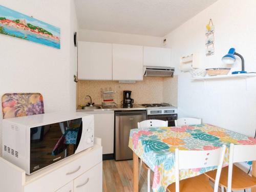 une cuisine avec une petite table et des placards blancs dans l'établissement Appartement proche du port à Gruissan, animaux permis, mini-box WiFi - FR-1-409A-21, à Gruissan