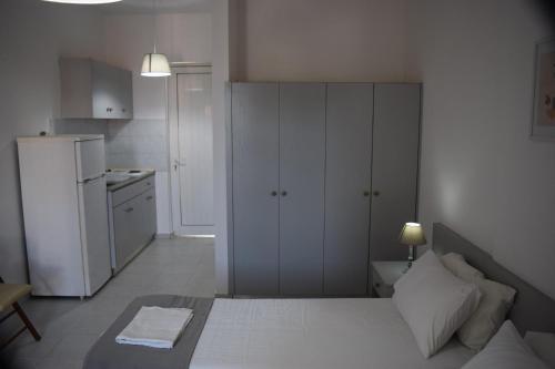 a bedroom with a white bed and a refrigerator at Lefteris Apartments in Ialysos Rhodes in Ialysos