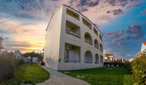 a white building with a sunset in the background at Lefteris Apartments in Ialysos Rhodes in Ialysos