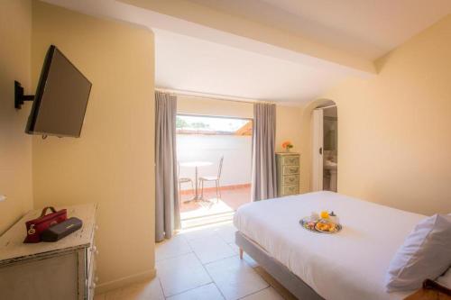 a bedroom with a white bed and a television at Hotel les Armoiries in Valbonne