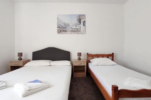 two beds in a room with white sheets and a picture on the wall at Private En Suite Room Matkovic. Kotor Bay in Bijela