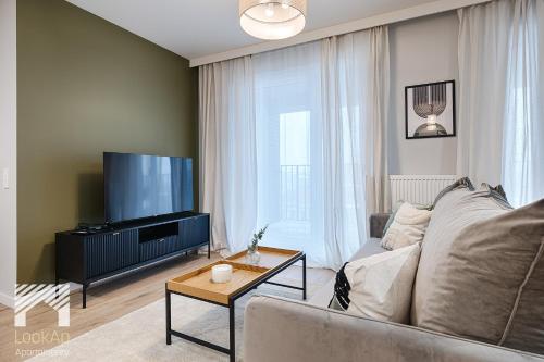 a living room with a couch and a flat screen tv at Fuzja II by LookAp in Łódź