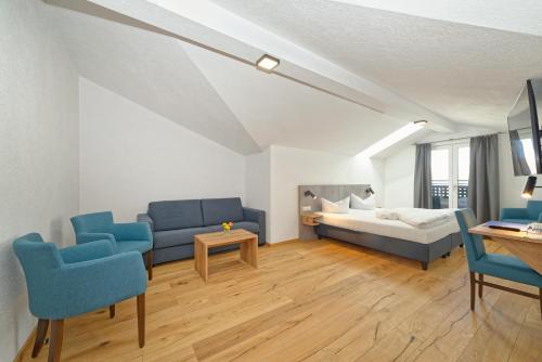 ein Wohnzimmer mit einem Bett und blauen Stühlen in der Unterkunft Hotel 17 Seen in Eggstätt