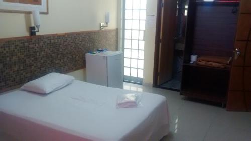 a bedroom with a white bed and a refrigerator at Hotel Dois Candangos in Brasília