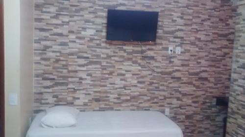 Hotel Dois Candangos في برازيليا: حمام بجدار من الطوب مع مرحاض وتلفزيون