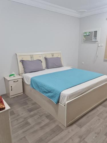 a white bedroom with a large bed with blue sheets at شقة عائلية -ليست فندقية- 8 دقائق بالسيارة للحرم أو قباء - in Medina