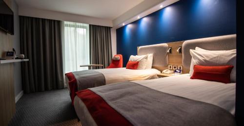 Cette chambre d'hôtel dispose de 2 lits et d'un mur bleu. dans l'établissement Holiday Inn Express London Stansted Airport, an IHG Hotel, à Stansted Mountfitchet