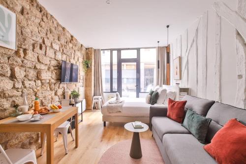 un salon avec un canapé et un mur en pierre dans l'établissement Studio 2pers#Mouffetard#Port-Royal#La Sorbonne, à Paris