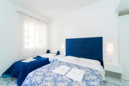 a bedroom with two beds and a blue headboard at La Casa di Aurora in Maiori
