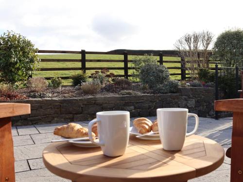 a table with two coffee cups and pastries on it at Little Orchard in Newton Abbot