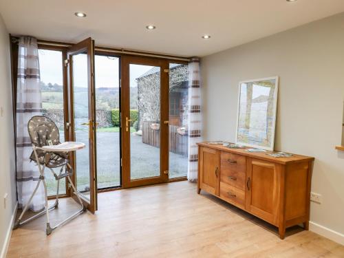 a room with a desk and a chair and glass doors at Little Orchard in Newton Abbot