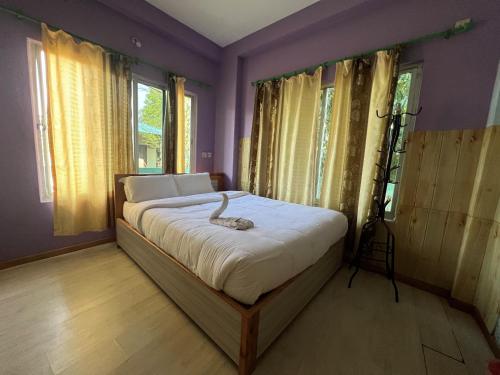 a bedroom with a large bed with purple walls and windows at Three Angels Lodge & Restaurant in Chitwan